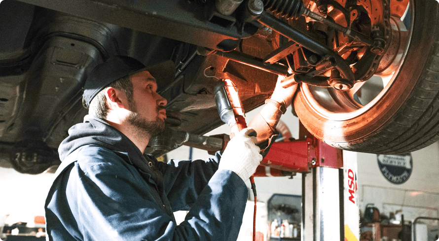 Car technician working on a car while it's lifted using a car lift